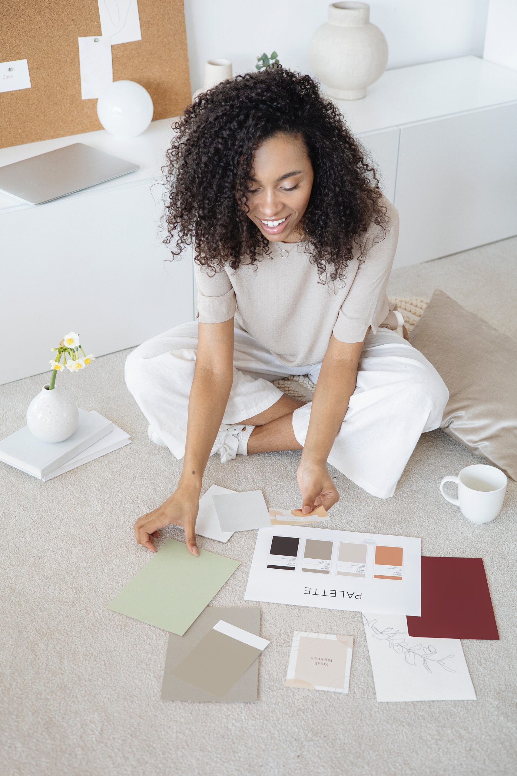A young woman sitting on the floor with color swatches in front of her, seemingly creating a color scheme for a project